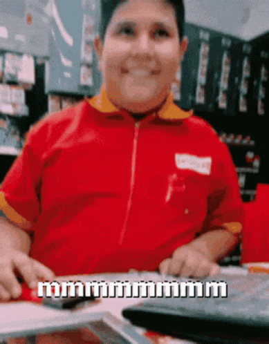 a man in a red shirt is sitting at a table with a keyboard and a calculator