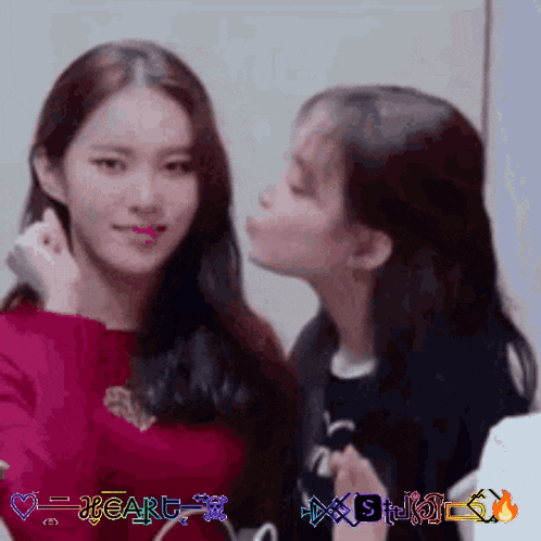 a girl kissing another girl on the cheek with the words heart written in the corner