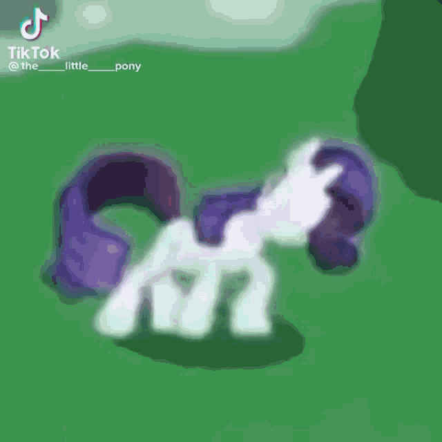 rarity from my little pony is standing in the grass .