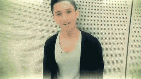 a young man is standing in front of a perforated wall .