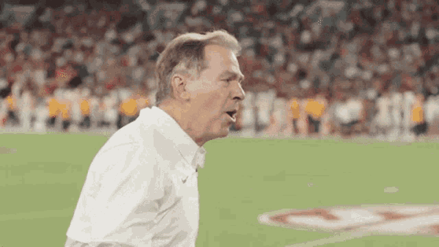 a man in a white shirt is standing on a football field