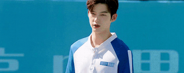 a young man wearing a blue and white baseball uniform is standing on a field .
