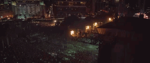 an aerial view of a crowd at a concert with flames coming out of the stands