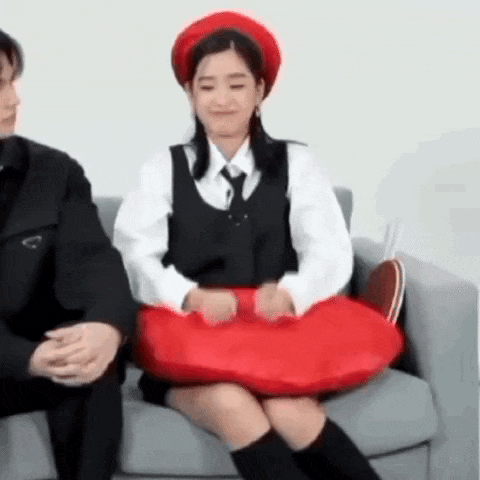 a man and a woman are sitting on a couch with a red pillow .