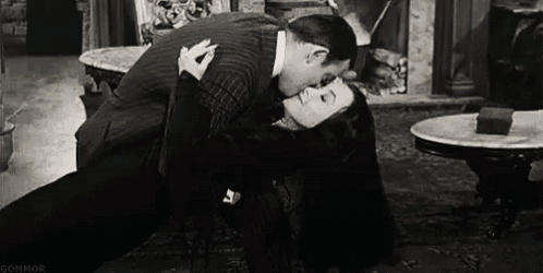 a man and woman are kissing in a living room .