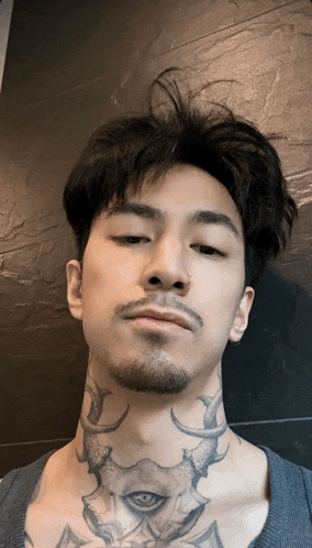 a man with a beard and a tattoo on his neck has his eyes closed