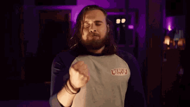 a man with long hair and a beard is making a funny face while wearing a netflix shirt .