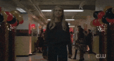 a woman is screaming in a hallway with balloons and a cw logo