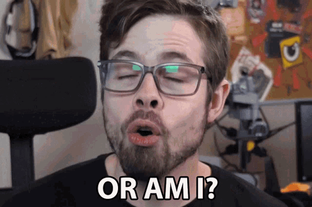 a man with glasses and a beard says " or am i " with his eyes closed