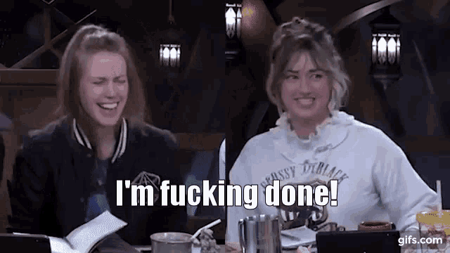 two women are sitting at a table and one of them is laughing and saying `` i 'm fucking done ! ''