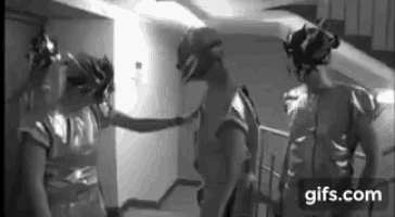a black and white photo of a man and a woman standing next to each other in a hallway .