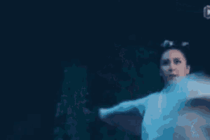 a woman in a blue dress is holding a sword in her hand in a dark room .