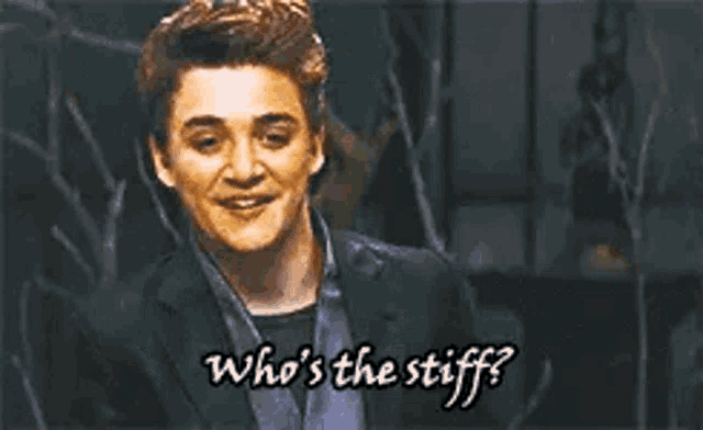 a man in a suit and tie is asking who 's the stiff ?