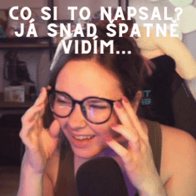 a woman wearing glasses holds her hands to her head with the words co si to napsal ja spad spatne vidim