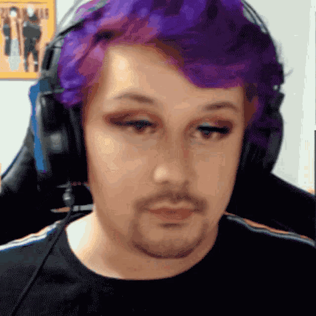 a man with purple hair and a beard is wearing headphones and makeup .