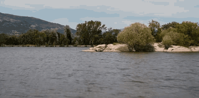 a man is standing on a rock in the middle of a lake