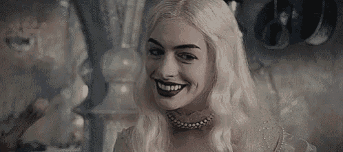 the white queen from alice in wonderland is wearing a pearl necklace and smiling .