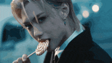 a man in a suit is licking a lollipop in his mouth