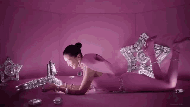 a woman in a pink bodysuit is laying on the floor and looking at jewelry