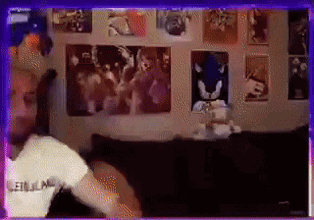 a man is standing in front of a wall with posters of sonic the hedgehog