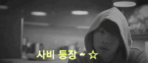 a black and white photo of a person wearing a hooded sweatshirt with korean writing on it