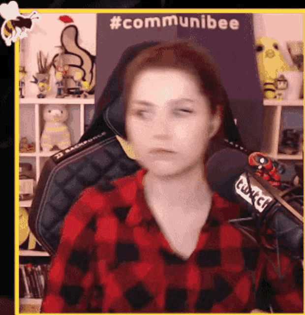 a woman in a plaid shirt is sitting in front of a microphone and a sign that says #communibee