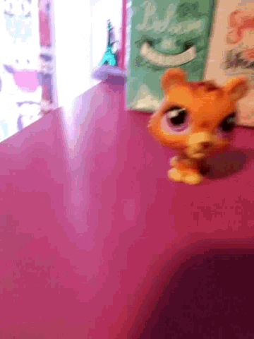 a stuffed animal is sitting on a pink table