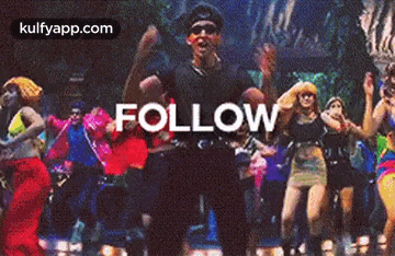 a man is standing in front of a group of people dancing and the word follow is on the screen .