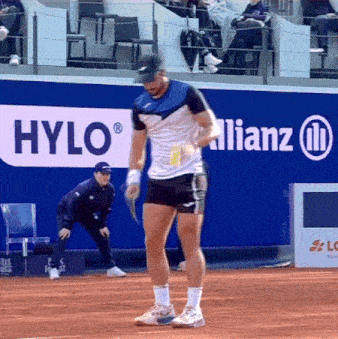 a man stands on a tennis court in front of an allianz sign
