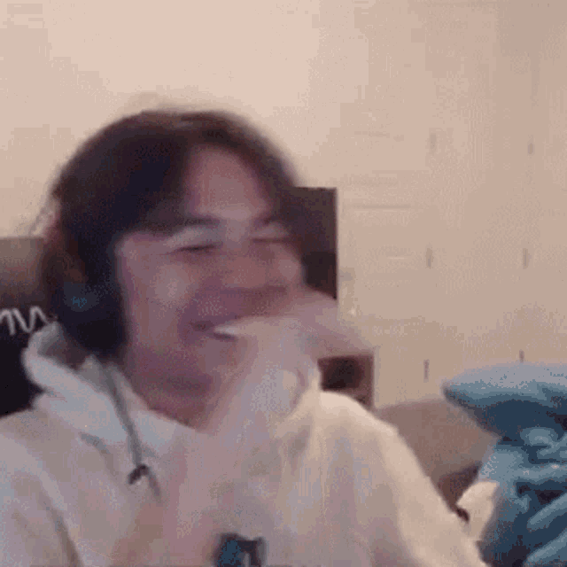 a man wearing headphones is laughing while sitting in a chair .