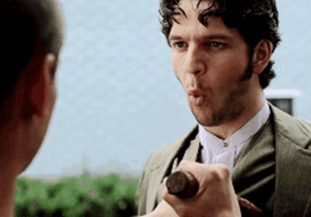 a man in a suit holds a bottle in his hand