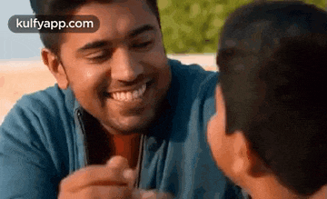 a man is feeding a child a piece of food and the child is smiling .