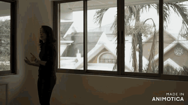 a woman stands in front of a window with the words made in animotica on the bottom right