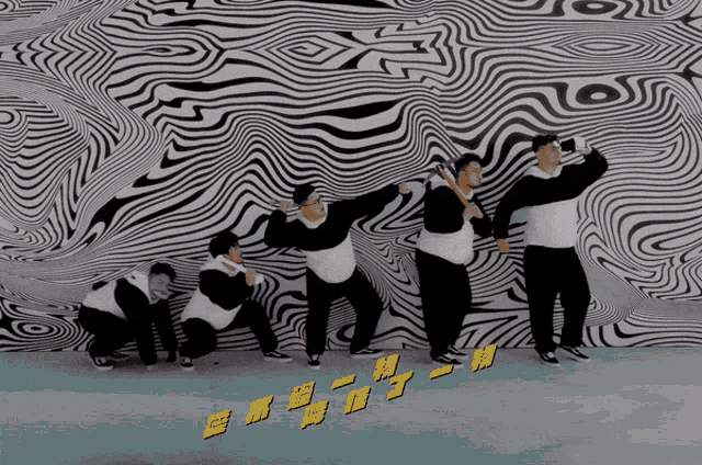 a group of people are dancing in front of a wall that has chinese writing on it