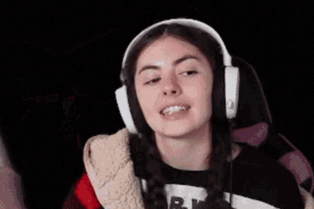 a woman wearing headphones and a plaid shirt is waving her hand in the air .