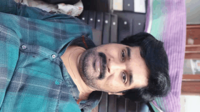 a man with a beard is wearing a plaid shirt and looking at the camera