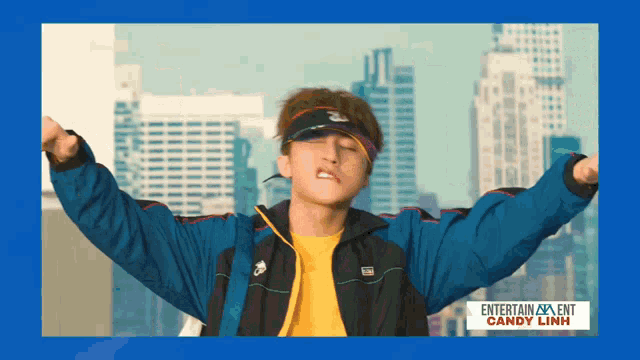 a man with his arms outstretched in front of a blue background that says entertainment candy linh