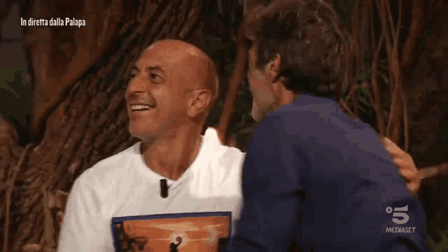 a man wearing a t-shirt with a picture of the lion king is laughing with another man