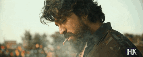 a man with a beard is smoking a cigarette and the word hk is on the bottom