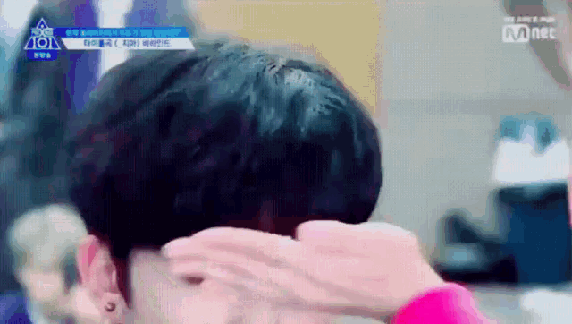 a close up of a person covering their face with their hand with a mnet logo behind them