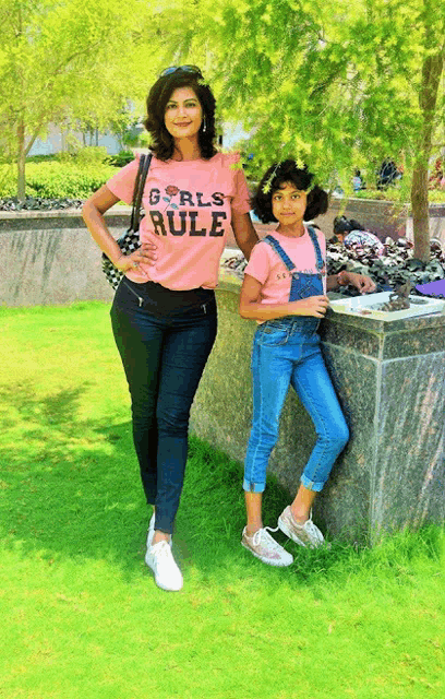 a woman wearing a pink shirt that says girls rule is standing next to a little girl