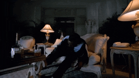 a man laying on a couch in a living room with a lamp