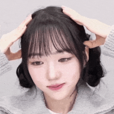 a close up of a woman 's face with her hands on her hair