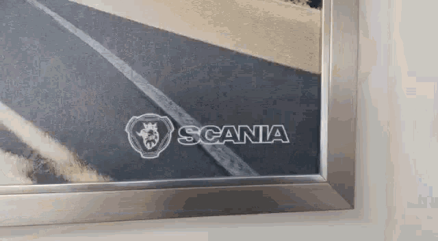 a framed picture of a road with the scania logo