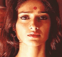 a close up of a woman 's face with a red spot on her forehead .