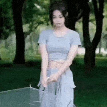 a woman in a crop top and skirt is holding an umbrella .