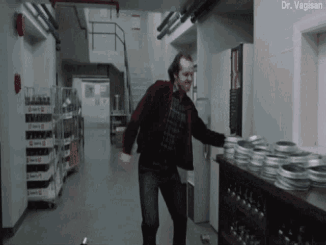 a man in a red jacket is standing in a hallway next to a shelf full of film rolls