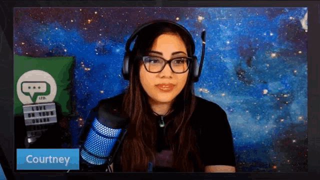 a woman wearing glasses and headphones stands in front of a microphone and says courtney