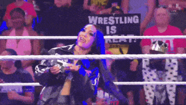 a woman in a wrestling ring with a sign that says wrestling is real behind her