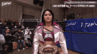 a woman wearing a princess belt is standing in front of a tjpw banner